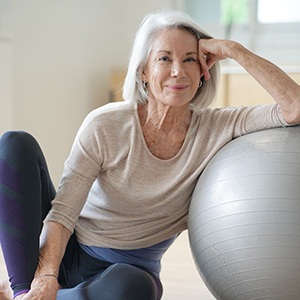 Senior woman smiling while resting against balance ball