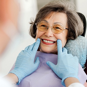 Dentist with blue gloves looking at senior woman's smile