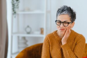 Woman holding side of face in pain.